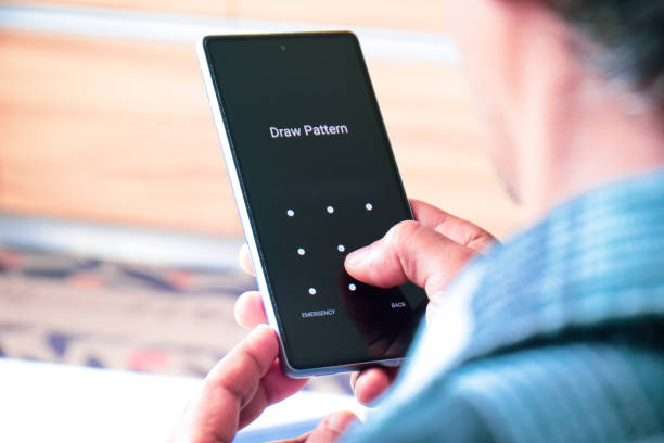 istock Man trying to unlock or set a new pattern screen lock for his mobile phone. Selective focus. 2202937806