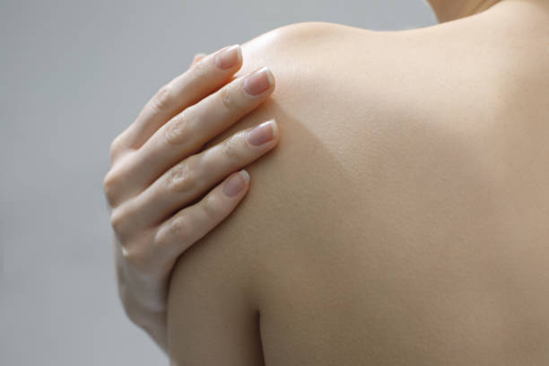 istock female hand on naked shoulder close up 2202947620