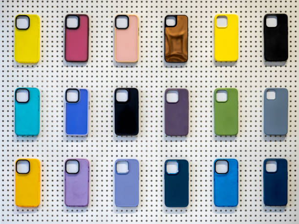istock Multicolor of back covers for smartphone isolated on white peg board background. Colorful mobile phone case with empty space for camera lens, showing on white wall in the mobile accessories shop. 2202950996