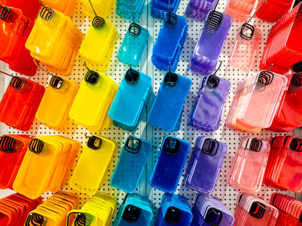 istock Transparent multicolor of back covers for smartphone. Colorful fluorescent mobile phone case with empty space for camera lens, hanging on hooks on shelf, white wall in the mobile accessories shop. 2202950997