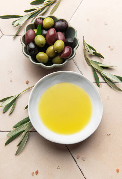 istock Olive oil and olives with olive branches resting on a tiled surface 2202969367