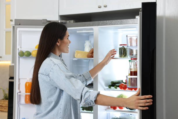 istock Young woman near modern refrigerator in kitchen 2202969620