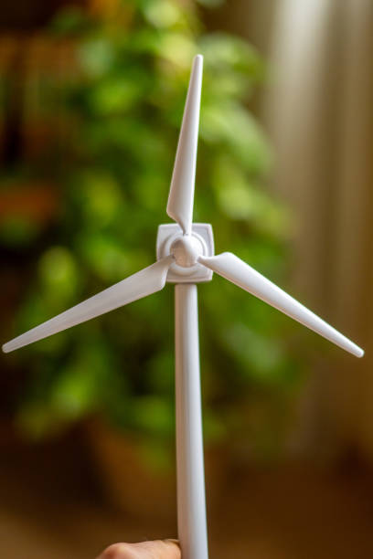 istock Hand holding a miniature wind turbine model symbolizes commitment to clean energy, representing alternative power sources and environmental sustainability 2202970381