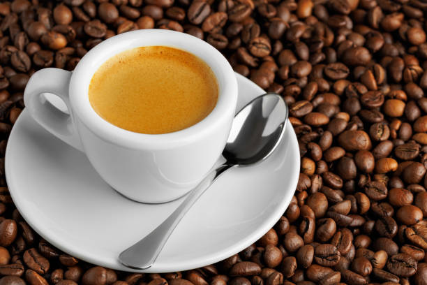 istock White espresso cup filled with fresh aromatic coffee, resting on bed of roasted beans, accompanied by a spoon, creating visually appealing composition 2202971110