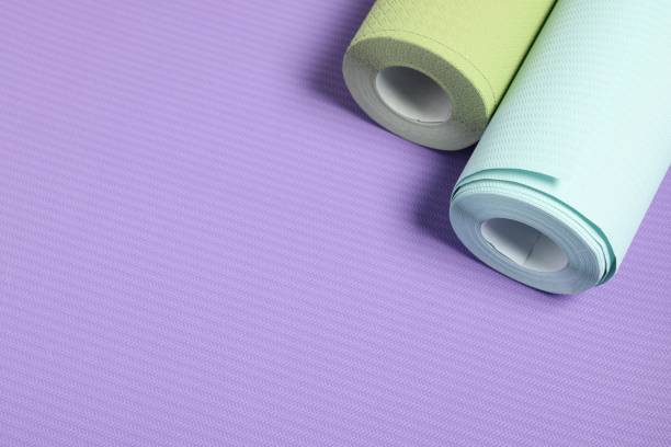 istock Two colorful wallpaper rolls on violet sample, above view. Space for text 2202972273