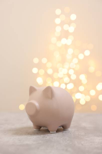 istock Piggy bank on grey table against blurred lights, space for text 2202972328