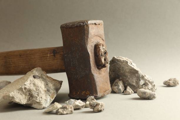 istock One sledgehammer and pieces of broken stones on grey background, closeup 2202972395