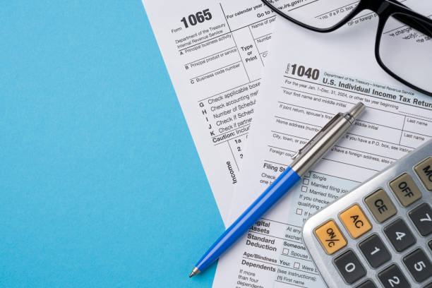 istock Top view of tax forms, calculator and pen on blue table 2202972482