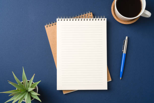 istock Top view of a workspace with a blank notebook, pen, coffee, and plant 2202972484
