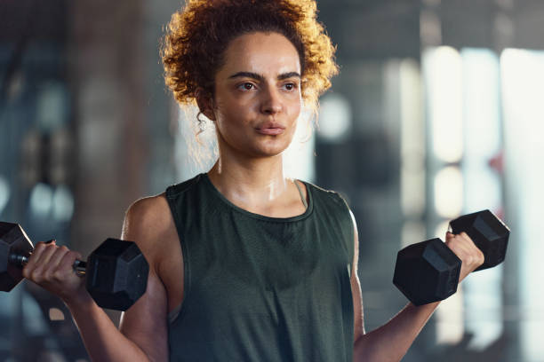 istock Young sportswoman exercising with weights in a gym. 2202977594