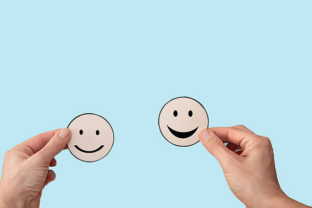 istock Hands holding two mood smiley faces on blue background, satisfaction rating concept 2202983505