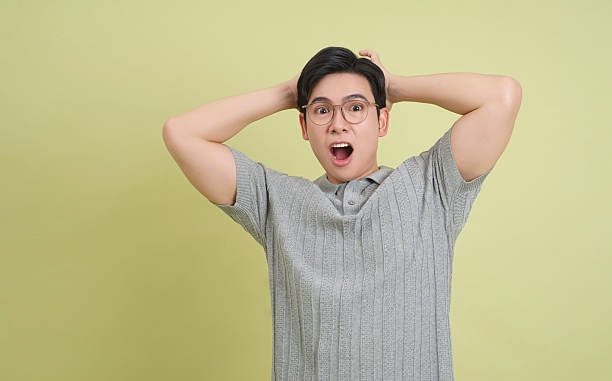 istock Surprised young man expressing shock in a casual setting with a light green background 2202984234