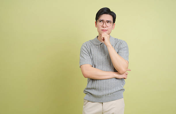 istock Thoughtful young man in gray sweater pondering ideas against a pale green wall 2202984268