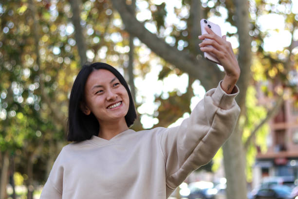 istock Young Asian woman smiling while taking a selfie 2202987587