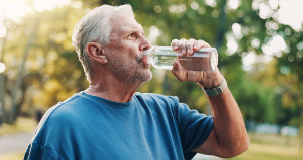 istock Fitness, senior man and drinking water at park for exercise break, hydration and thirsty from running. Detox, male runner and liquid bottle for wellness, cardio workout or marathon training in nature 2202993827