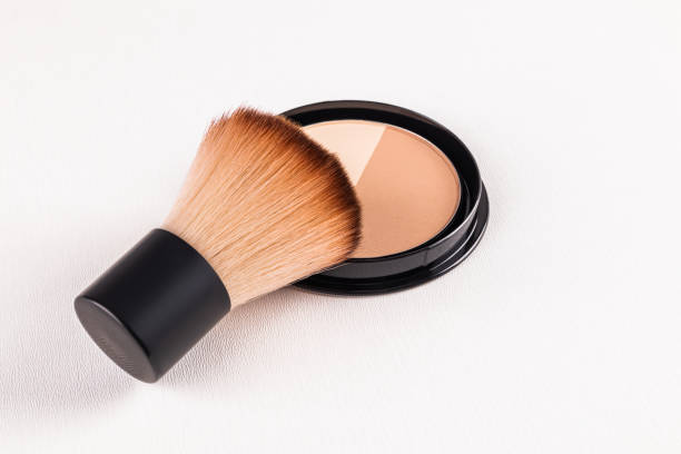 istock A fluffy short makeup brush rests on a block of compact powder with two different tones. An open pack of powder. texture of decorative cosmetics. 2202994851