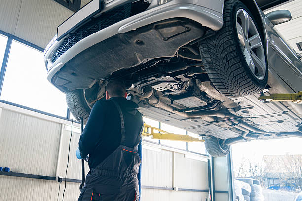 istock Serviceman checks car suspension on a column lift in car service. 2202995667