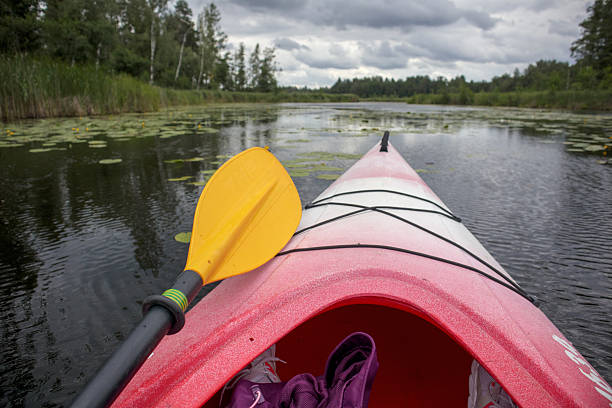 kayak floating on water with forest and sky in the background.