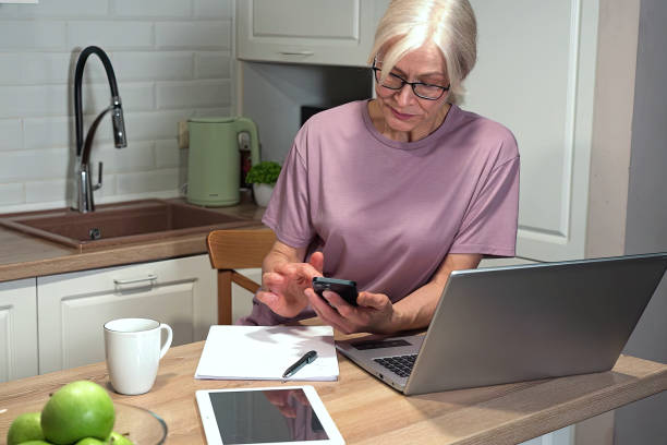 istock Senior woman working remotely in kitchen 2203000109