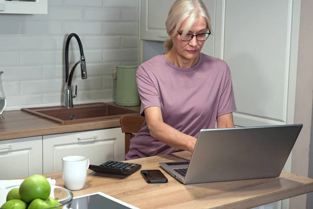 istock Elderly woman typing on laptop and calculator 2203000121