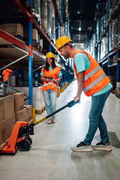 istock Warehouse workers managing inventory and moving goods with pallet jack 2203001493