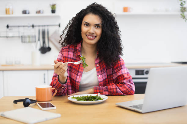 istock Young woman enjoying healthy salad during work session at home kitchen 2203006668