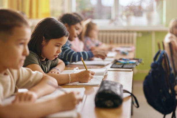 istock Schoolgirl writing in a notebook during a class in the classroom. 2203007261