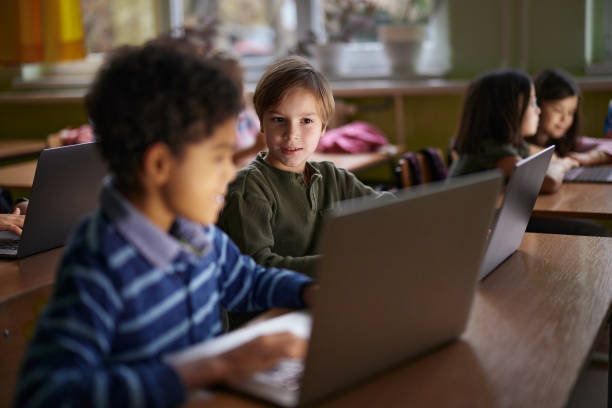 istock Schoolboy and his friend e-learning over laptop in the classroom. 2203009307