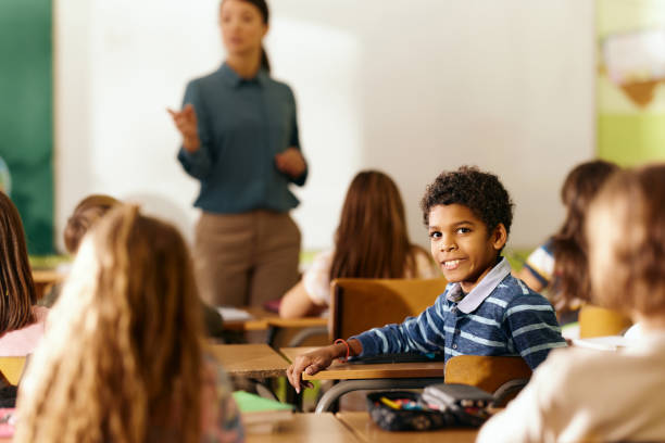 istock Happy black schoolboy enjoying on a class in the classroom. 2203009472