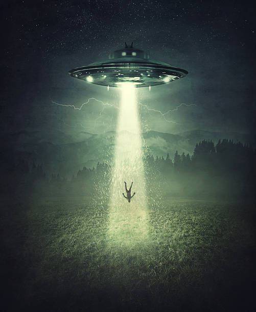istock Mysterious alien spaceship abduction scene. Surreal concept with a levitating human stolen by the light of an UFO ship in a dark night on a open field 2203018049