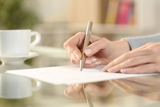 Woman hand signing contract on a transparent desk stock photo