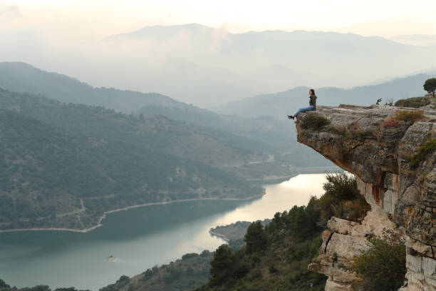 istock Woman sitting in a cliff contemplating nature 2203020081