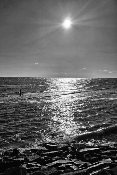 Ɓ&W photo of a Chesapeake Bay winter sunrise, sun reflections and rocky shore