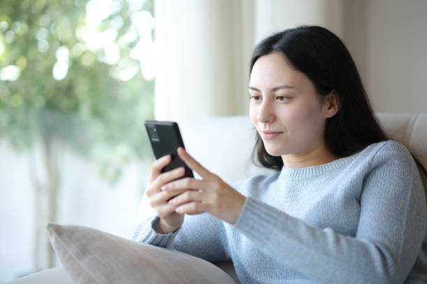 istock Asian woman using smart phone at home 2203027441