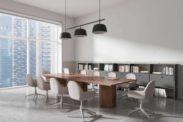 istock Modern conference room interior with large wooden boardroom table, comfortable chairs, and bookshelves, overlooking city skyline. 3D Rendering 2203028842