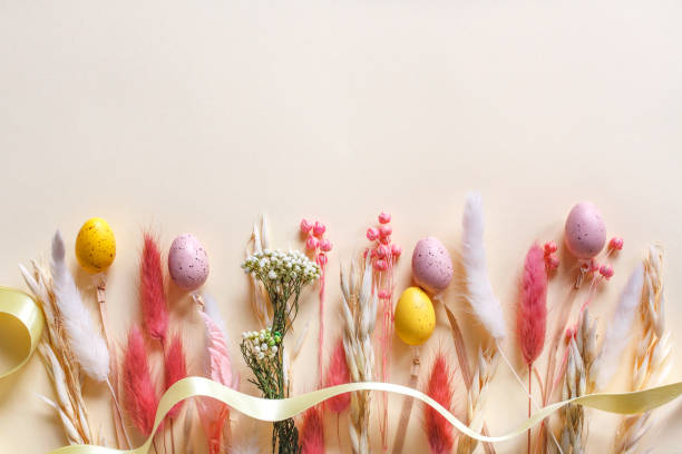 istock Happy Easter banner design, colorful Easter eggs and pastel dried spring flowers on beige background with copy space 2203029771