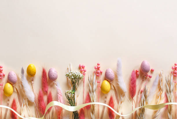 istock Easter colorful flat lay with  colorful Easter eggs and pastel dried spring flowers on beige background with copy space 2203029772