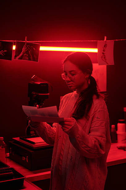 istock Girl Working with Photo Prints Selecting Images in Darkroom Studio 2203032736