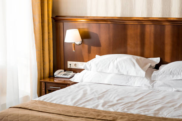 istock A hotel-type bed with white sheets, pillows and a bedside table in a hotel room or home bedroom. Space for the text. Enjoying the morning concept. 2203032984