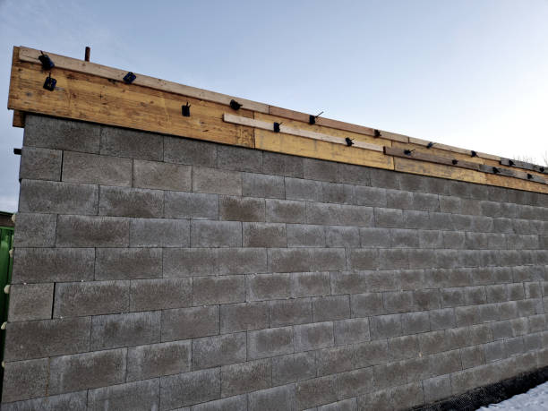 istock construction of a concrete wall from concrete blocks filled inside with reinforcing steel and concrete. gray stepped wall of hollow bricks on the foundation of a house or fence, foam, plastic 2203033594