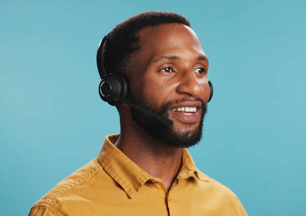 istock Black man, headset and call centre operator in studio, hotline employee and blue background. Male person, telemarketing consultant and helping with customer care, professional service and advisor 2203034263