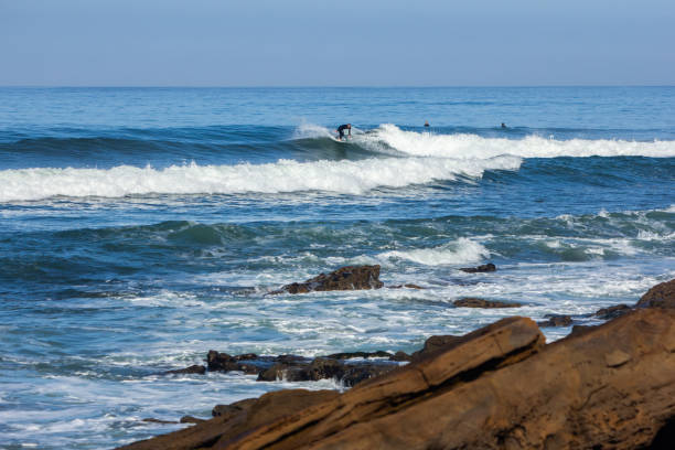 istock Wide angle of surfers in the blue ocean 2203035373