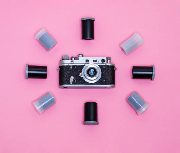 istock Retro camera surrounded by boxes with photo film on a pink background. 2203036254