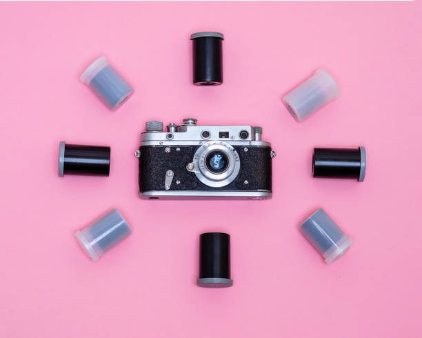 istock Retro camera surrounded by boxes with photo film on a pink background. 2203036259