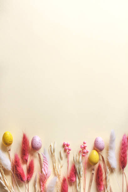 istock Happy Easter vertical banner design, colorful Easter eggs and pastel dried spring flowers on beige background with copy space 2203036810
