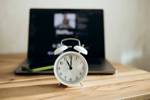 istock White alarm clock and laptop at the workplace, close-up, office work concept. 2203050460