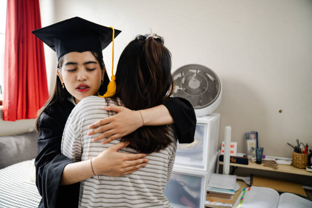 istock Smiling sisters gesturing peace at graduation 2203051125