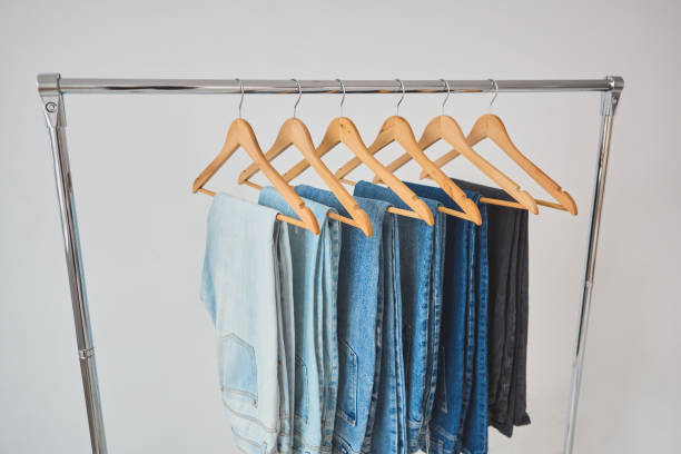 mobile clothes hanger on a white wall background. a set of jeans of various colors mobile clothes hanger on a white wall background. a set of jeans of various colors on wooden hangers. store concept clothes hanger rod stock pictures, royalty-free photos & images