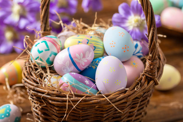 istock Decorated Easter eggs in a basket with purple daisies 2203055732