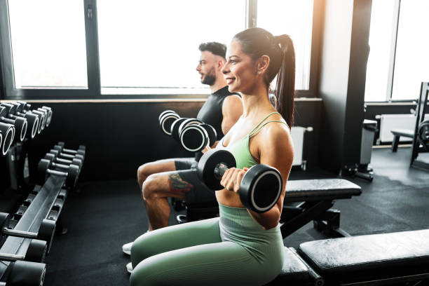 istock Couple Lifting Dumbbells on Gym Bench 2203056497